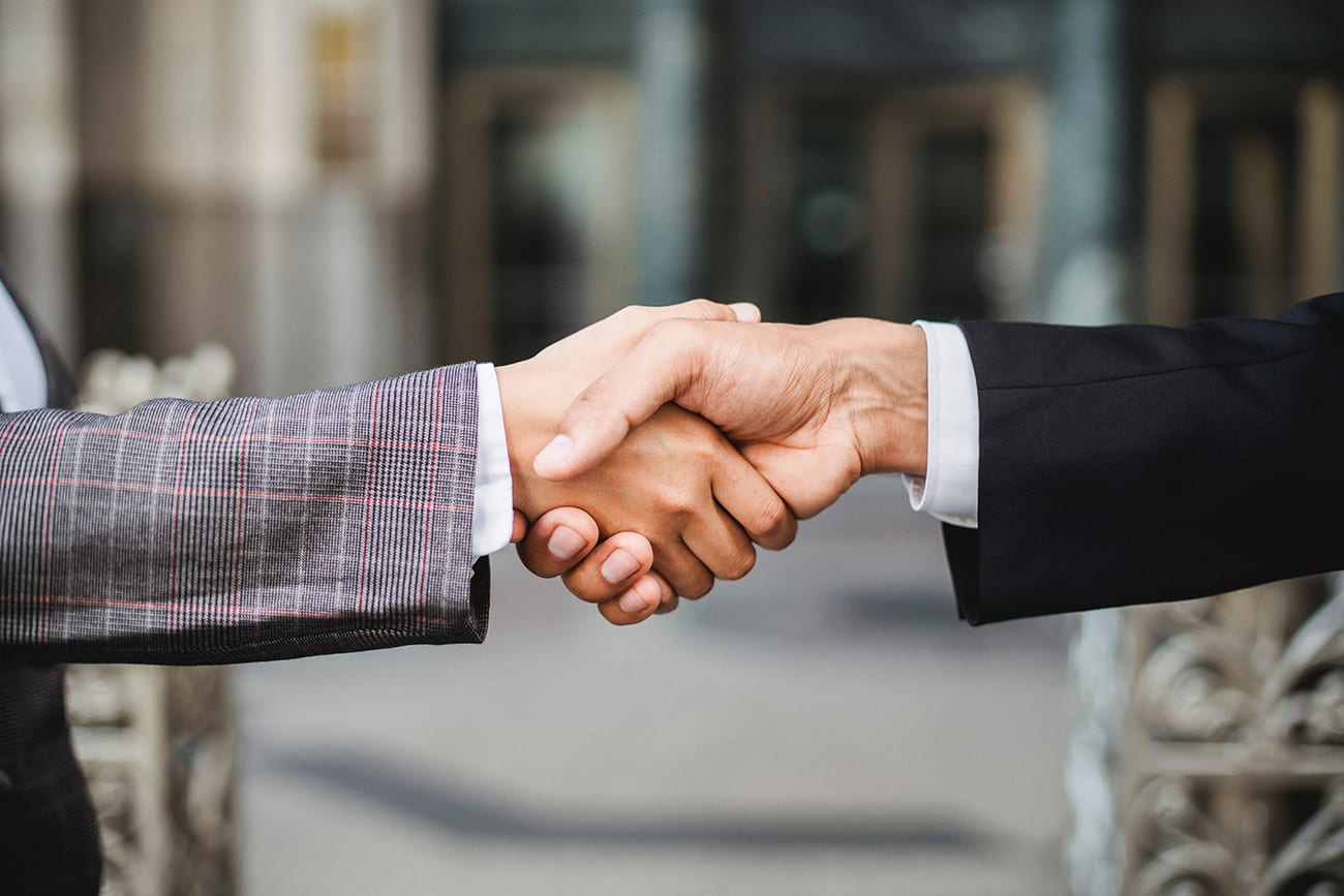 Two people in a handshake showing a partnership with Trustwell Insurance